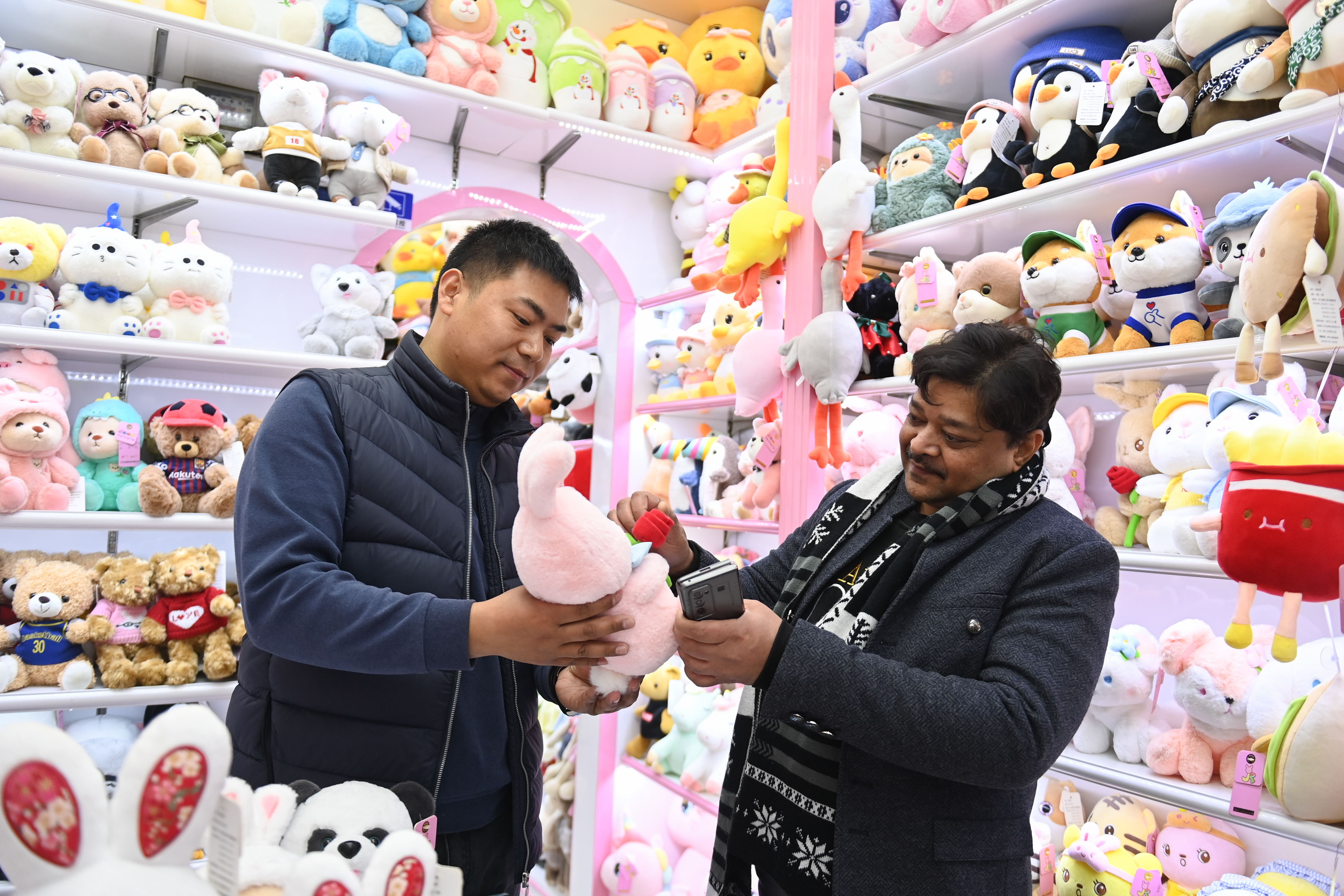 2023年2月2日，來自印度的客商（右）在義烏國際商貿(mào)城的一家玩具店鋪內(nèi)選購。